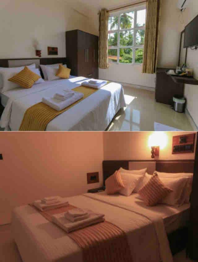 A well-lit bedroom features two beds with neatly arranged blankets and pillows. Large windows provide natural light, revealing outdoor greenery. A dark wooden wardrobe and a wall-mounted television are present, contributing to a functional yet comfortable space for relaxation.
