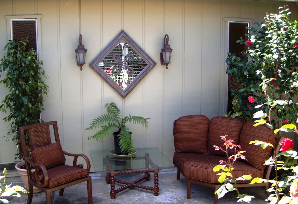 Private patio is lined with ornamental plants and comfortable seating.