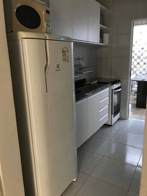 Cozinha com todos os eletrodomesticos, panelas , pratos e copos .