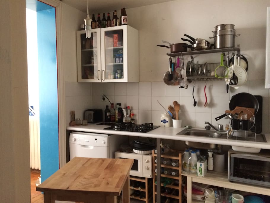 Vue de la cuisine : lave-vaisselle, four micro-ondes, four électrique, 4 plaques cuisson gaz, grille-pain. Il y a également un grand réfrigérateur avec compartiment congélateur.