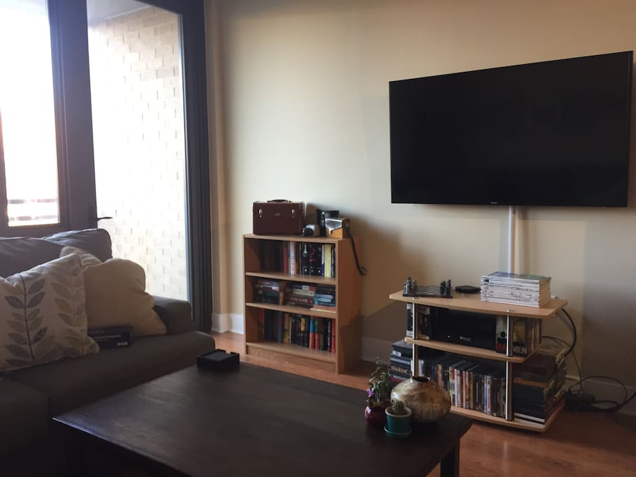 Living room features cozy sectional couch, 60 inch television and access to balcony
