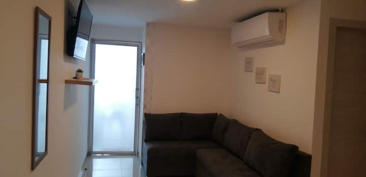 Un salon dans un mini-appartement avec Internet,  climatisation, TV et  Netflix.