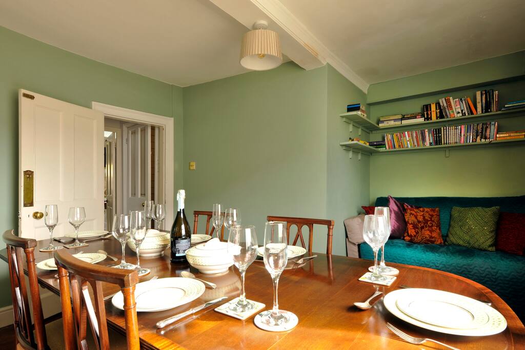 Dining room with Georgian mahogany table, wood-burning stove, sofa, books and games.