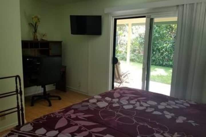 Dormitorio principal con lanai privado, escritorio y televisión vía satélite montada en la pared.