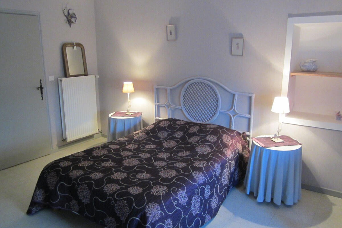 紫色卧室配有藤条床头板和圆形床头柜。