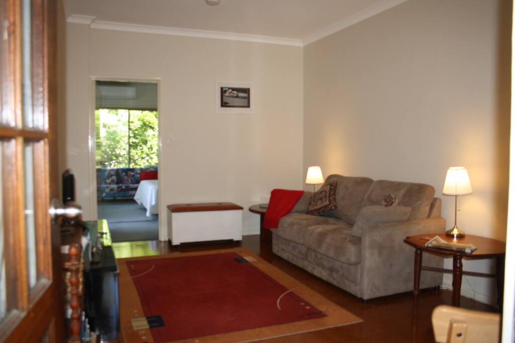 Sofa bed in lounge with lamps, door to the bedroom with the air conditioner.