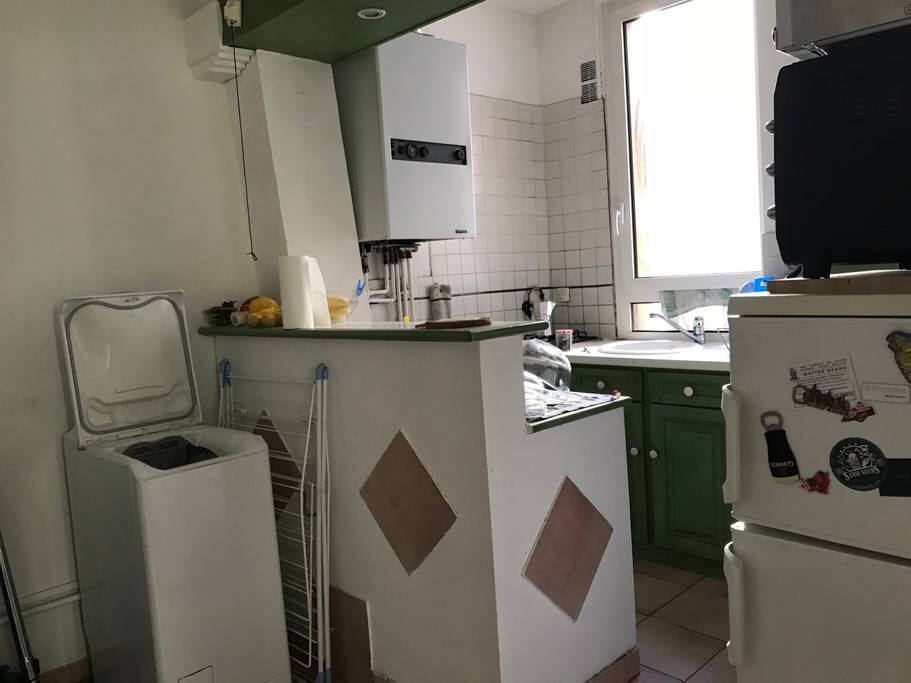 Vu depuis l'entrée sur le coin sèche linge et étendoir, séparé de la cuisine par une table bar