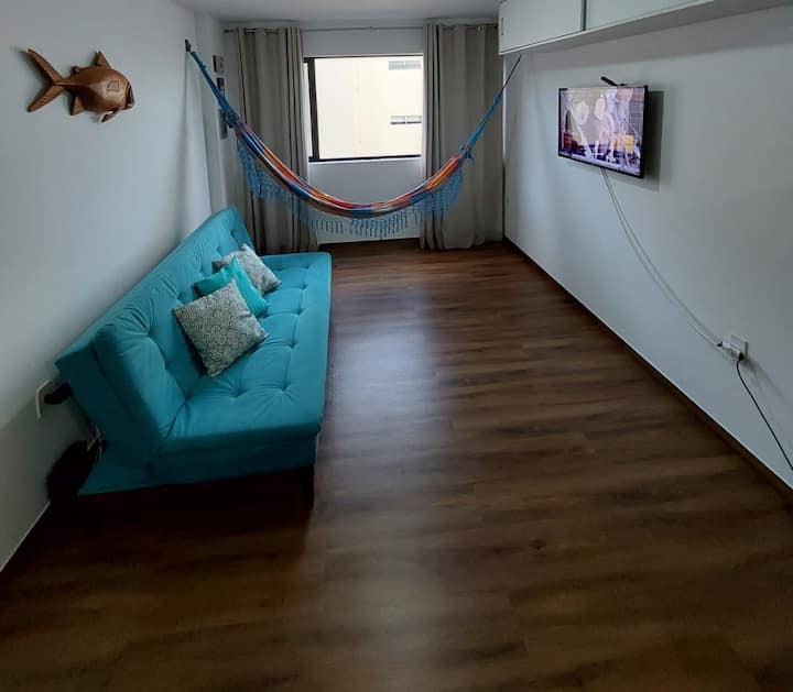 Sofa iliyo na kitanda kizuri cha watu wawili sebule, runinga janja na feni.