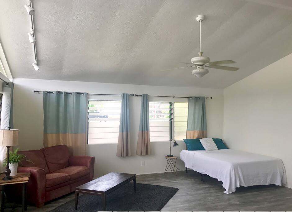 Open floor plan, love seat couch and queen mattress with lots of natural lighting