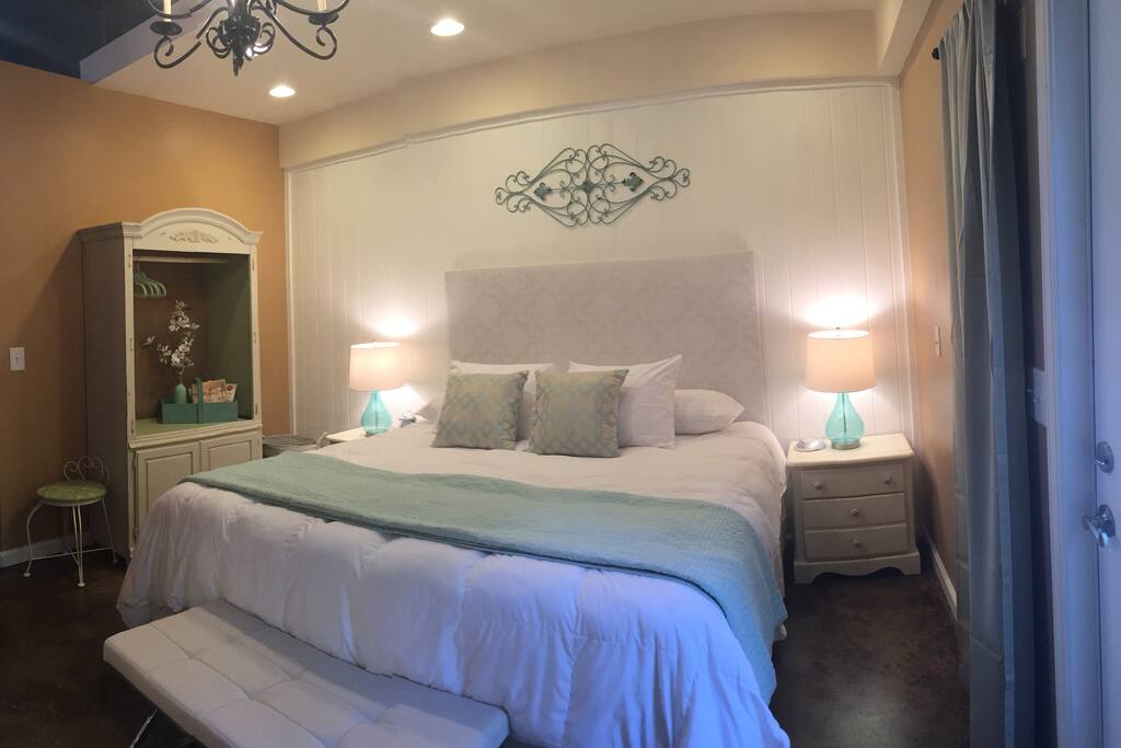 The relaxing bedroom features an open armoire with hangers to hang clothes. It also has shelves and baskets below for more storage. There is also a white noise machine and a fan for your comfort. A full length mirror and seating too!