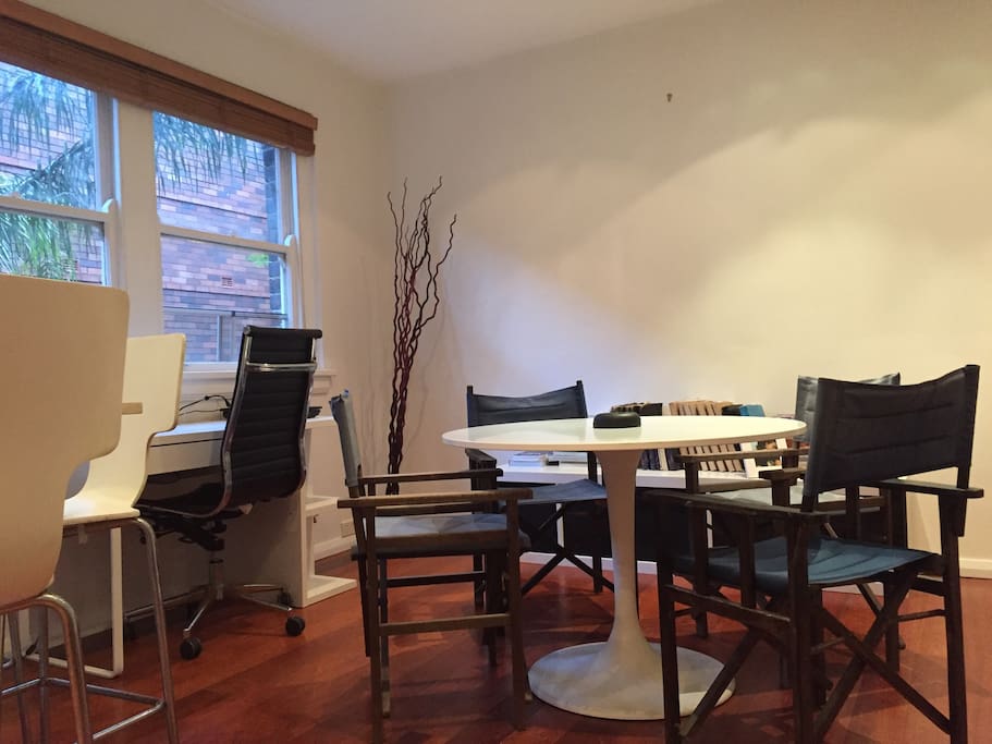 View from the kitchen into the living room with a dining table and a desk.