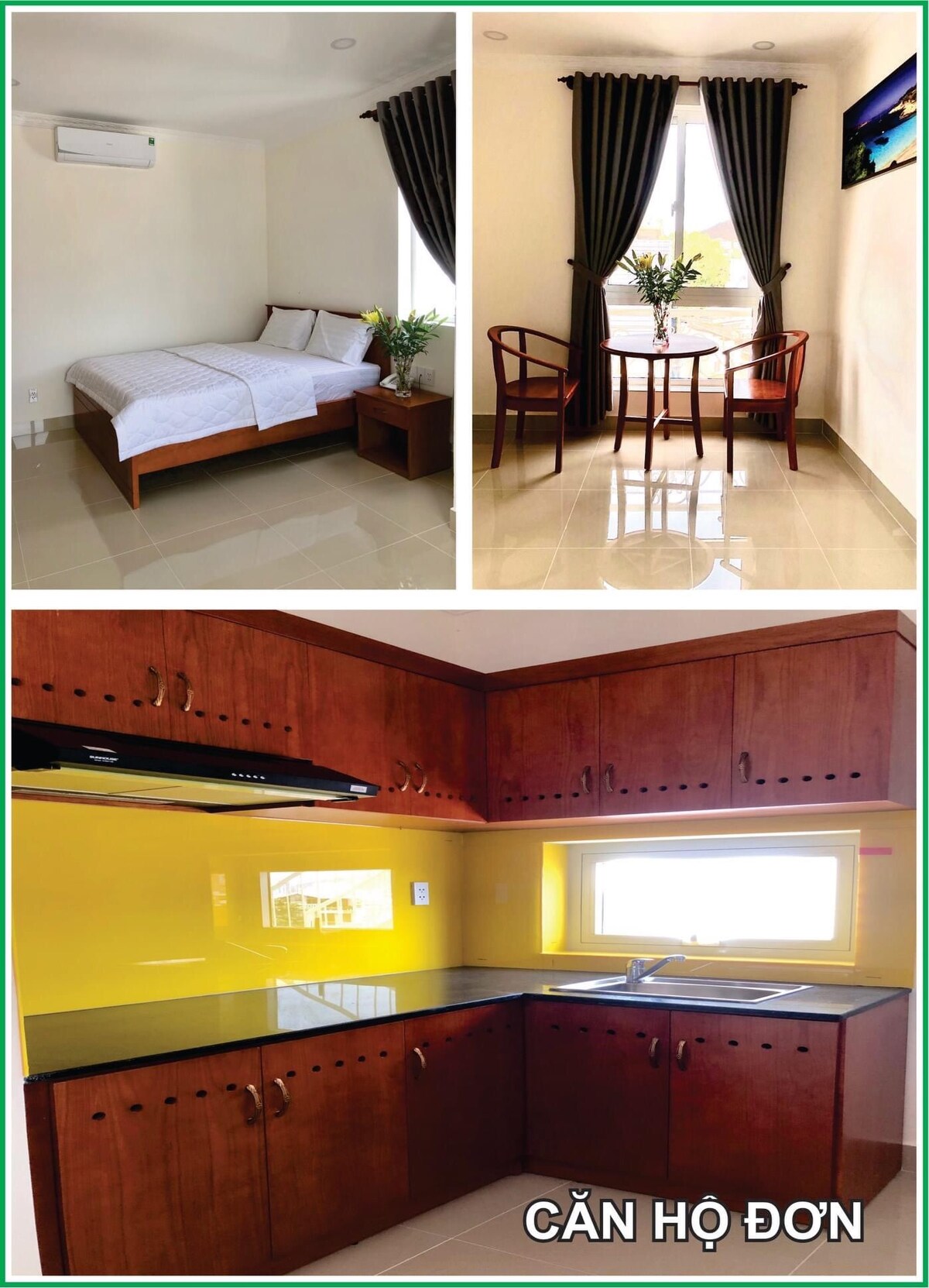 A bright studio apartment features a spacious bed with a simple wooden nightstand and a small table set with two chairs. A window with dark curtains allows natural light to fill the room. The kitchen area is equipped with wooden cabinets and a black countertop.