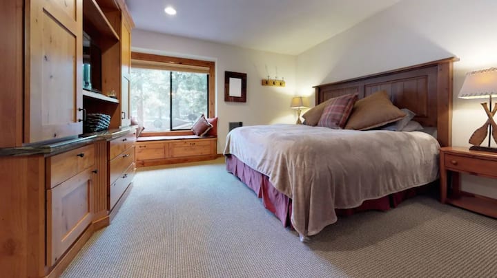 Relax in the spacious primary bedroom featuring a plush king-size bed, custom built-ins & warm wood accents. The en suite bathroom includes a walk-in shower and heated tile floors for a cozy, spa-like experience - perfect after a day outdoors.