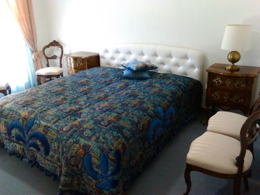 Finely furnished private double room with a king bed, bedside tables, and chairs