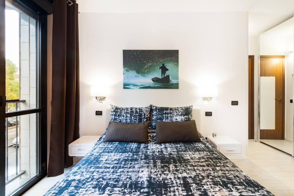 Foto verificata air BnB spaziosissima camera da letto con grande finestra affacciata sul parco davanti all' appartamento.tende oscuranti danno anche un tocco elegante alla stanza