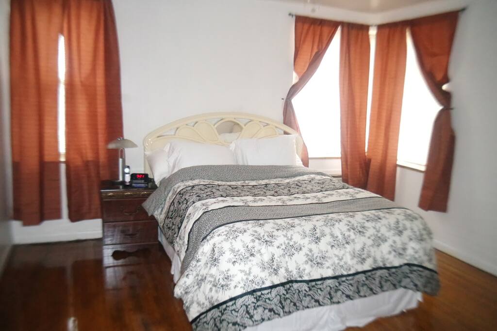 Bedroom with queen-sized bed and night stand, alarm clock and phone.
