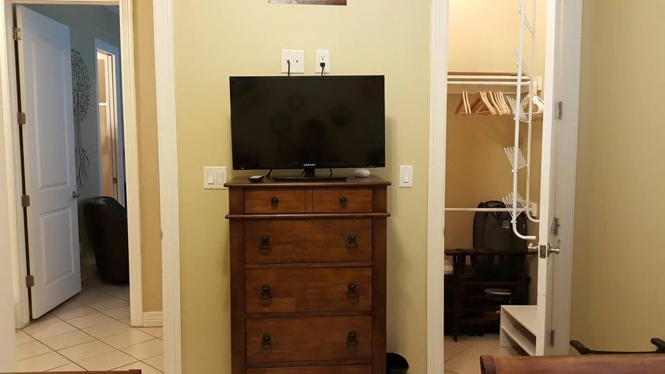 De kamer heeft een kist, een flatscreen-tv en een grote kast met een schoenenrek en artikelen voor het strand.