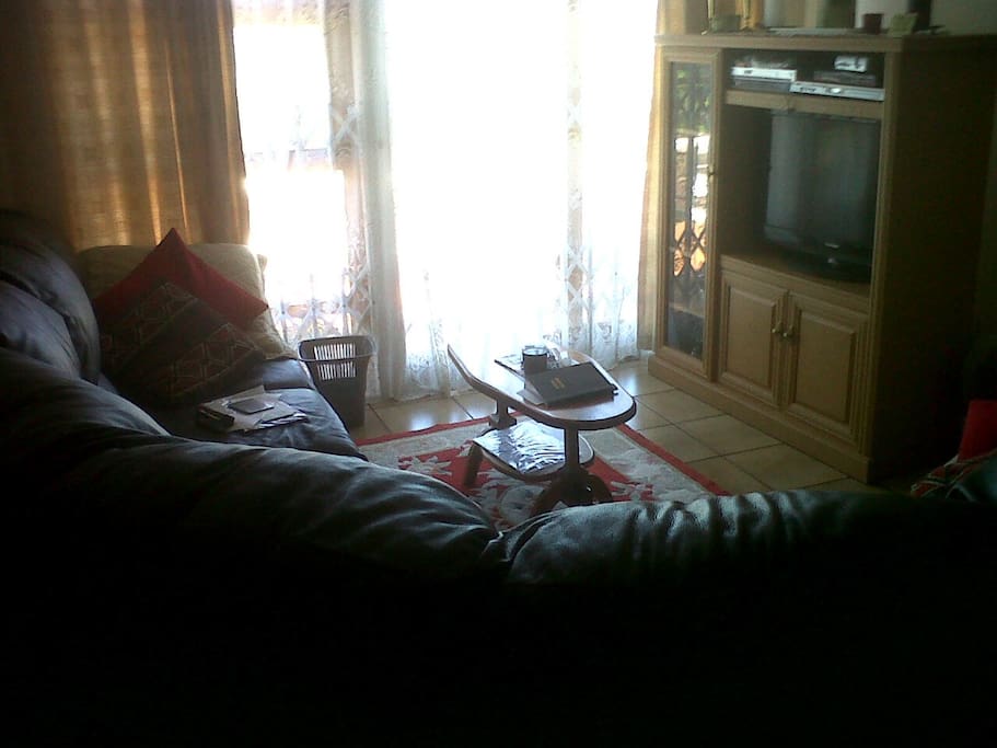 TV lounge with a curved leather couch, flat screen TV and DSTV