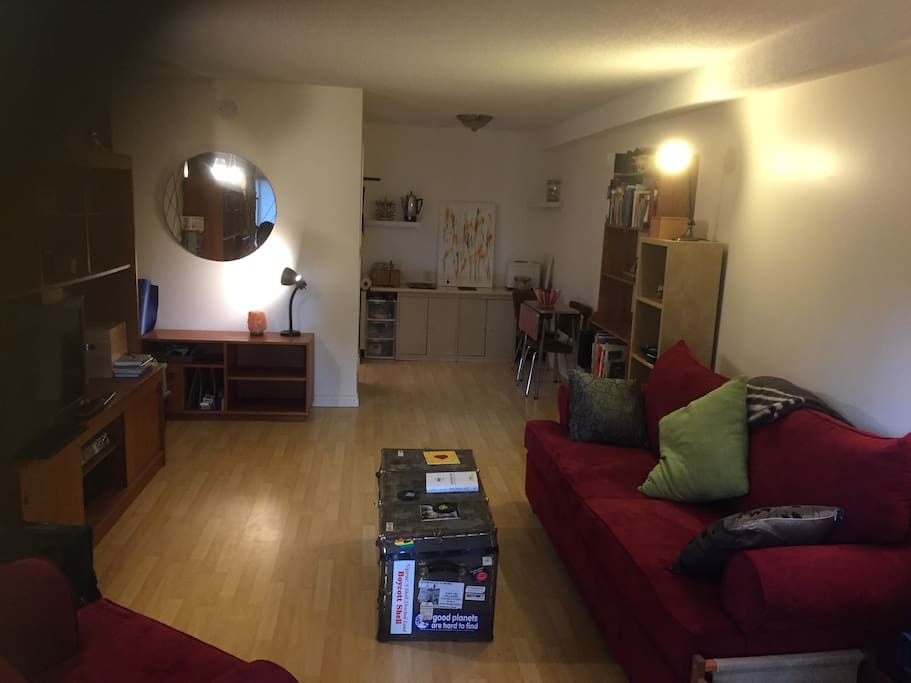 View from patio door into living room and dining area. Galley kitchen is behind the mirrored wall at the end (left)