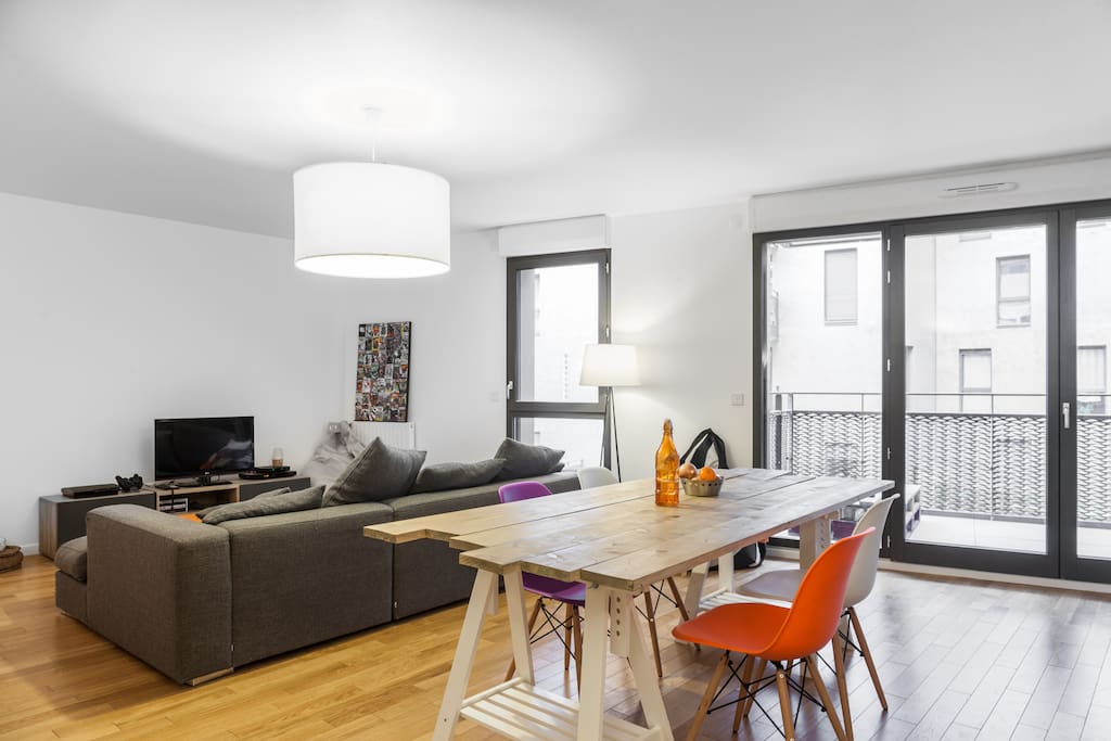 Salon lumineux et contemporain, canapé moelleux, ouvrant sur un balcon ensoleillé et une cour intérieure calme