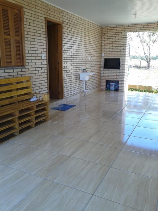 Garagem espaçosa e área de serviço com churrasqueira com acesso a área aberta nos fundos.