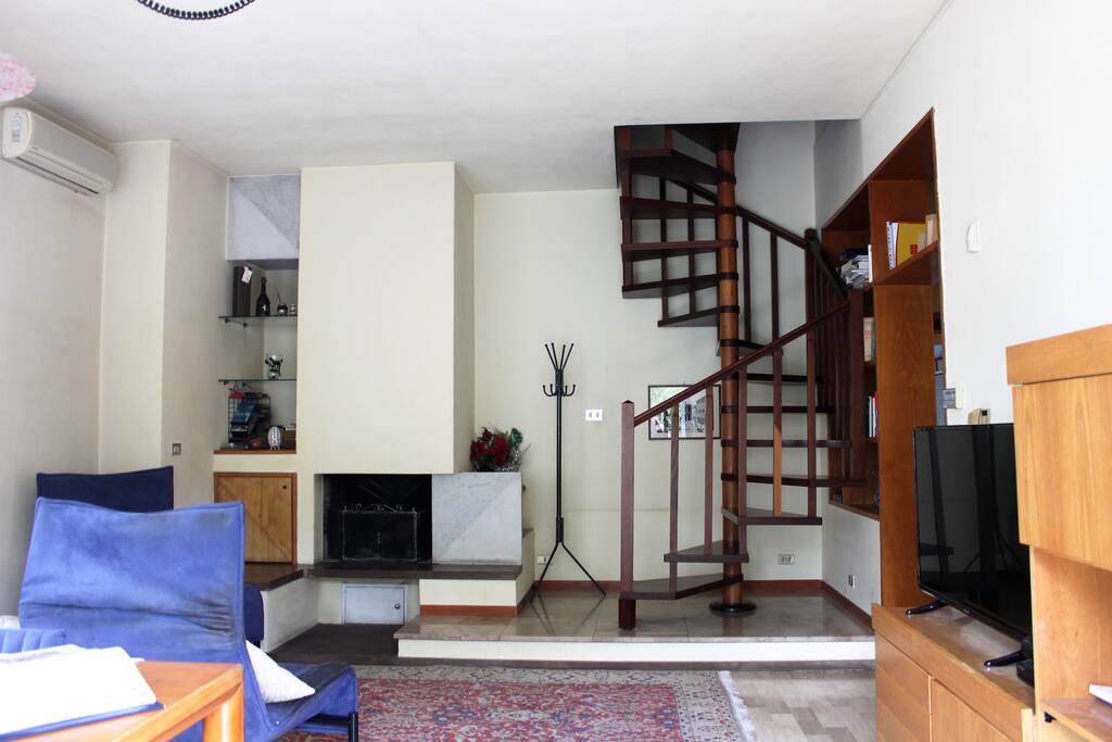 la sala/salotto con camino e scala di accesso alla mansarda