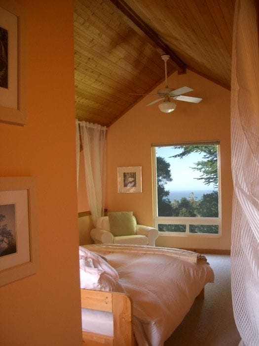 主卧配有羽绒被和白色窗帘，可欣赏海景