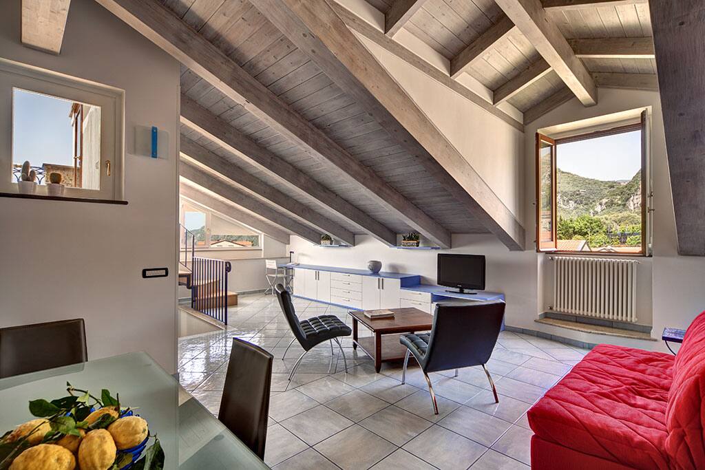 The main living area has a bright red sofa bed, comfortable modern chairs, a flat screen satellite television and dining table.