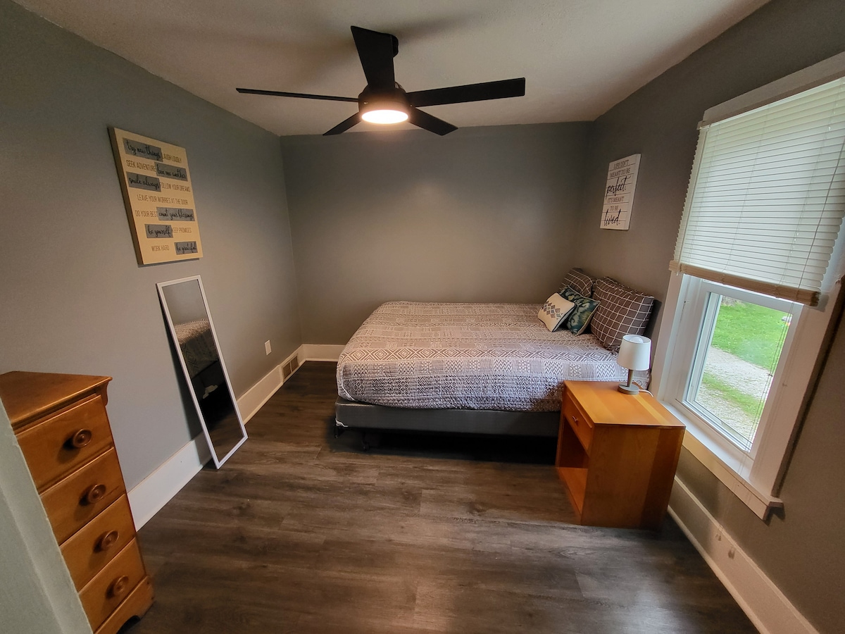 Chambre arrière située en dehors de la cuisine. Dans la chambre, il y a un lit queen size, un ventilateur de plafond télécommandé avec lumière et un miroir intégral pour se préparer à une soirée en ville.