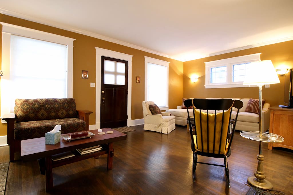 View of the entire living room and front door from the dining room entrance. The front door is the main entrance to the house and leads directly into the living room.
