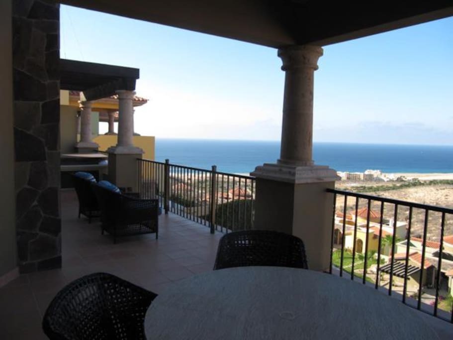 The balcony with BBQ grill and outdoor dining area; hot tub in the rear.