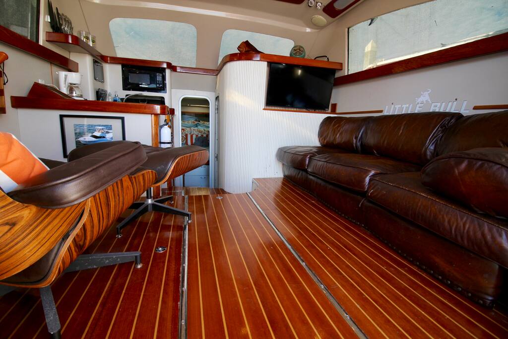 Spacious salon (living room) with a 40” LCD tv, premium leather couch & extra comfy eames lounge chair.