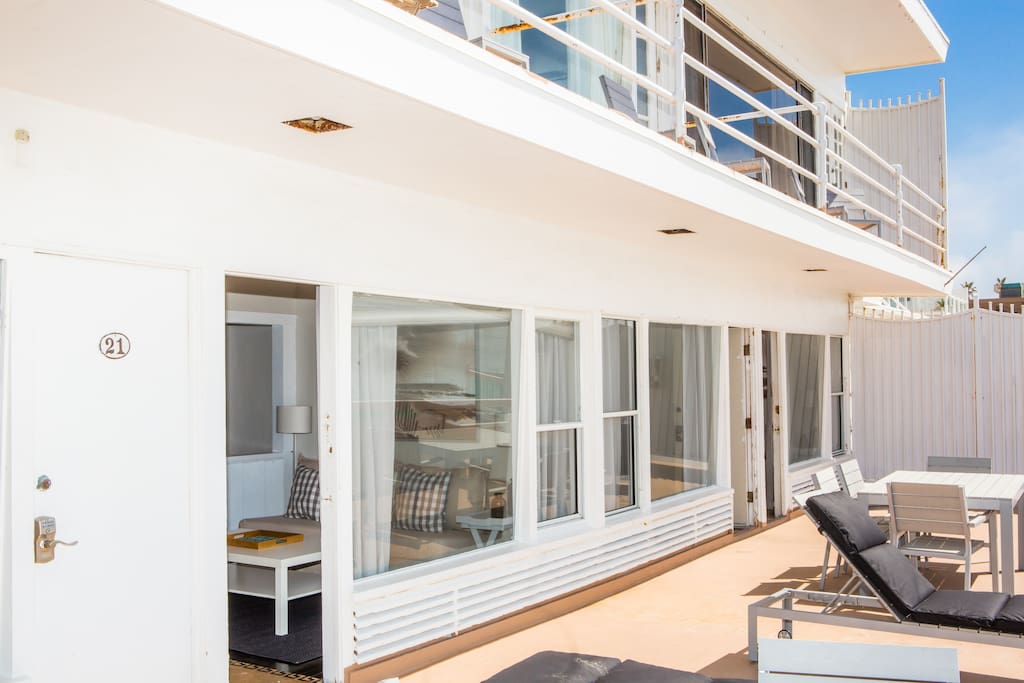 Studio connects to a semi private deck with lounge chairs and a patio table