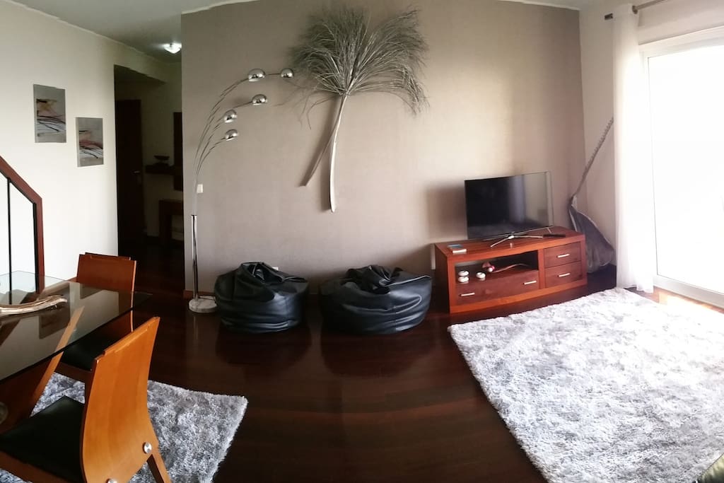 Sala de estar com TV e acesso à varanda.