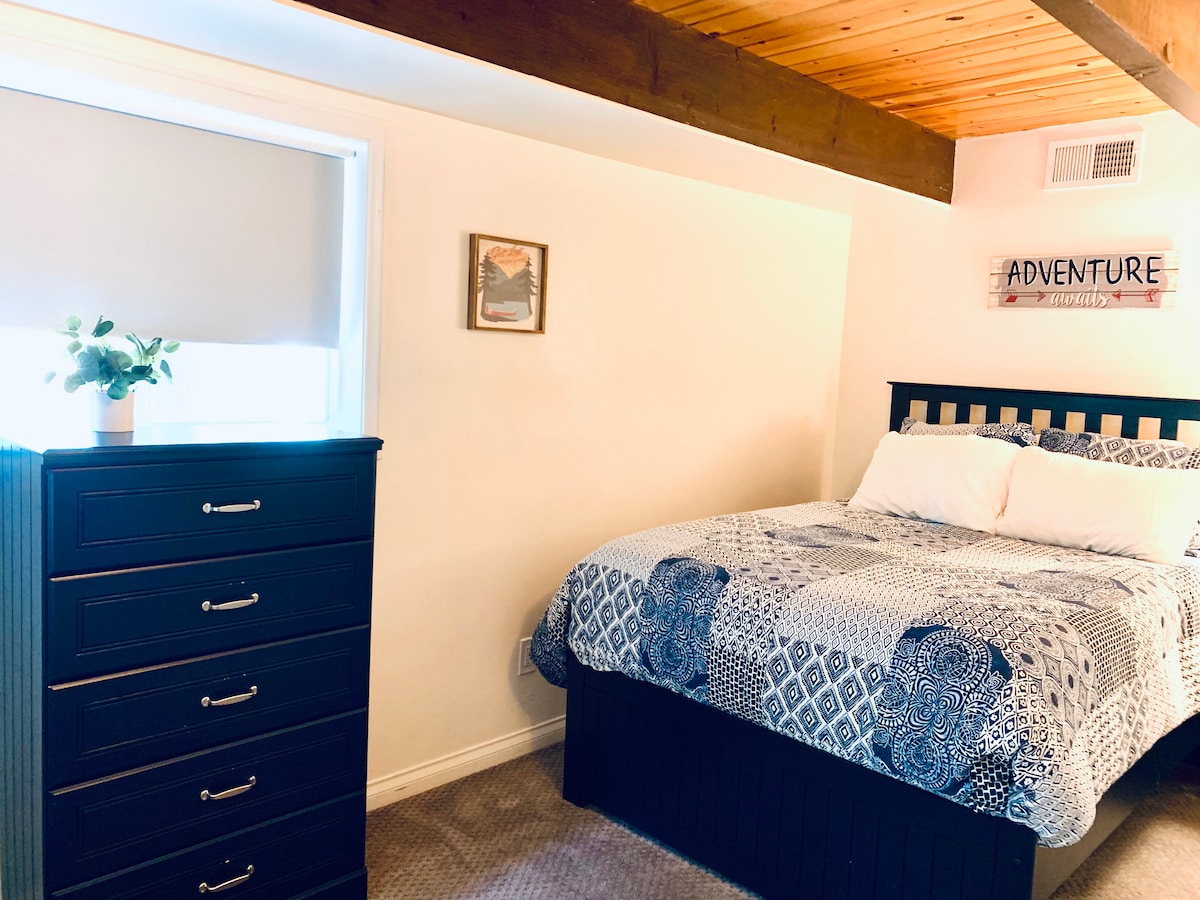 غرفة نوم رابعة في الطابق السفلي من الغرفة العائلية مع مدخل للسطح السفلي ومطبخ صغير ومغسلة وحمام.