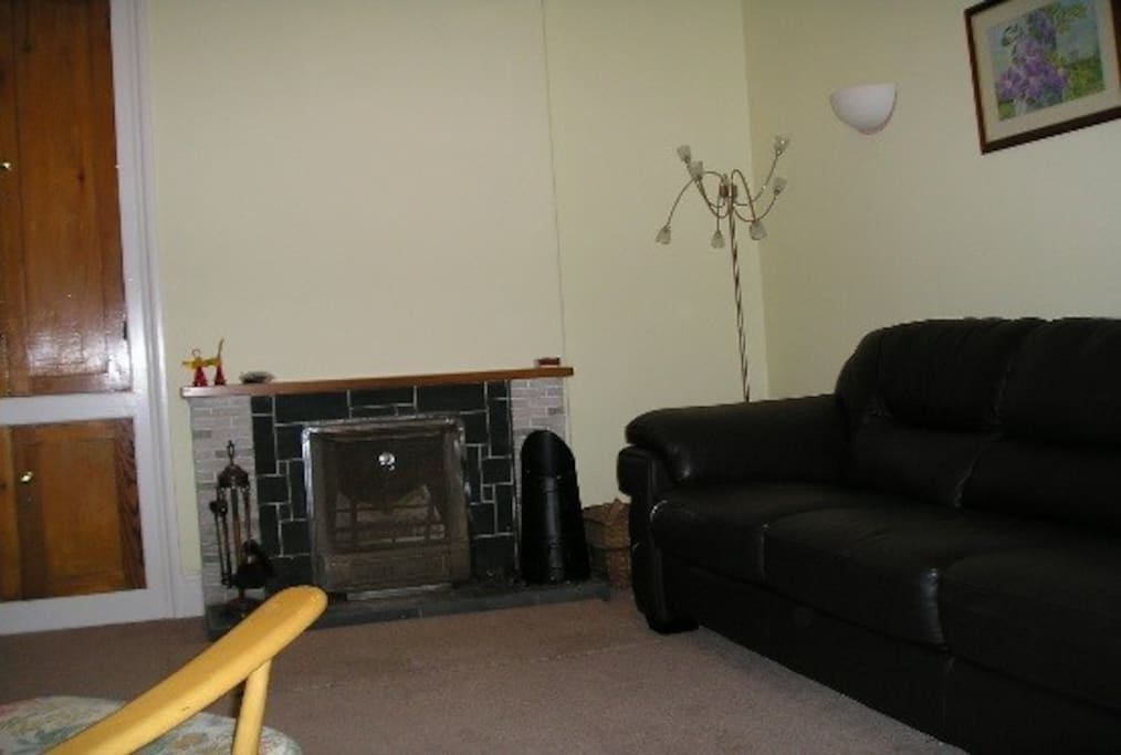A cosy lounge with large sofa, two armchairs and open fire.
