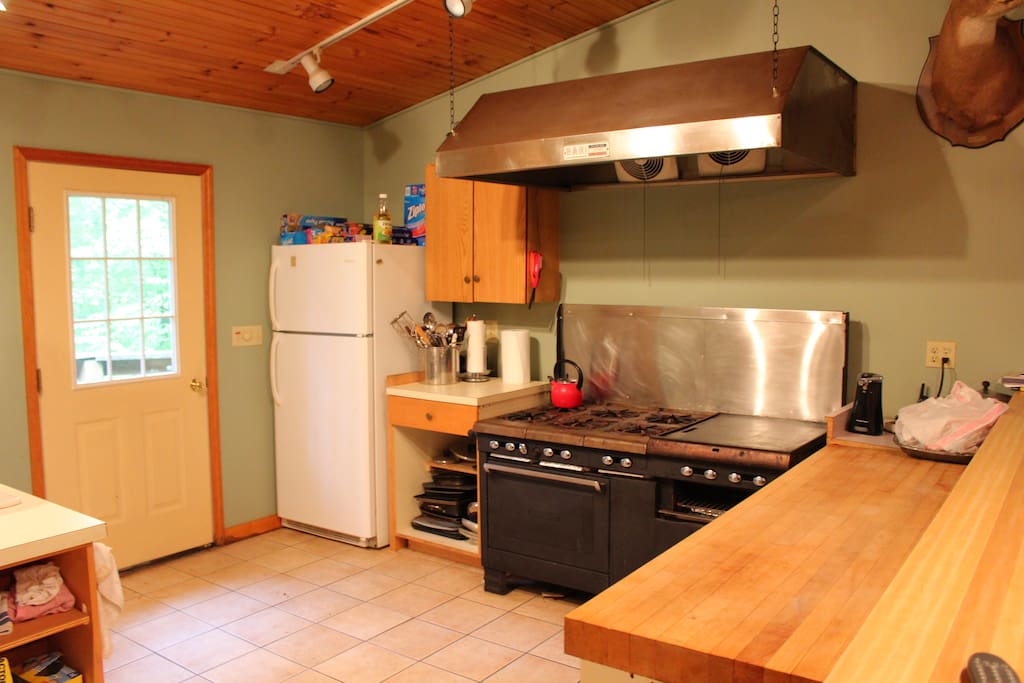 Industrial stove with butcher block counter top, underneath breakfast bar. Outdoor grill on the porch outside the kitchen. Perfect for big meals. 3 full size refrigerators for stocking food and drinks.