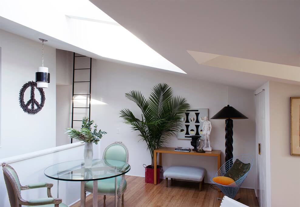 Dine under the skylight on a Danish modern table seated on Louis XVI chairs.