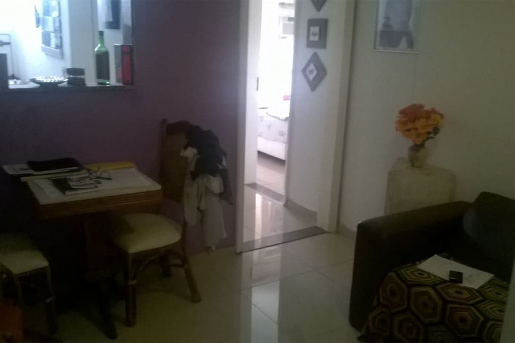 Sala de estar composta por sofá e mesa com 3 cadeiras.