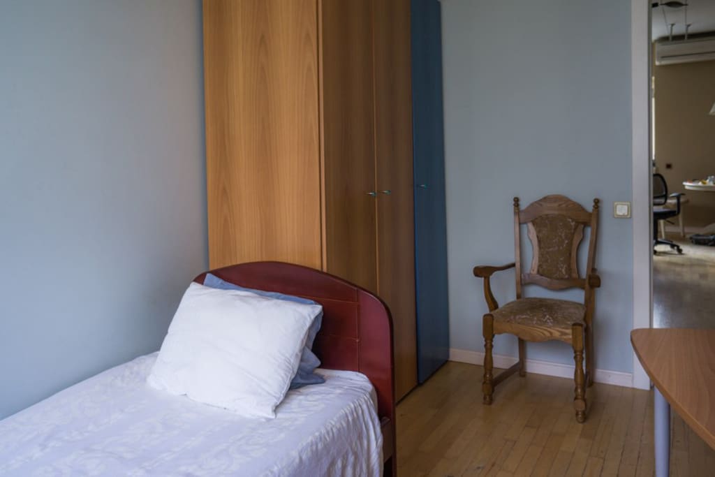 the view of the room — there is a cupboard, a table suitable for working and the bed