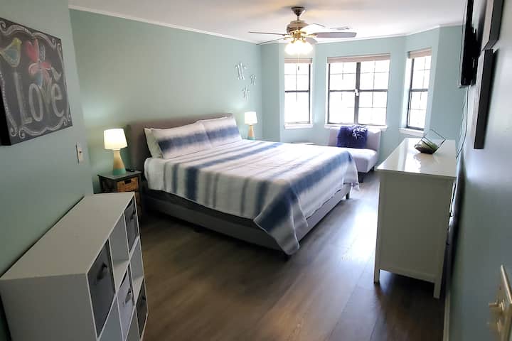 Master suite direct naast de woonkamer met verduisterende gordijnen en een gemonteerde tv. 