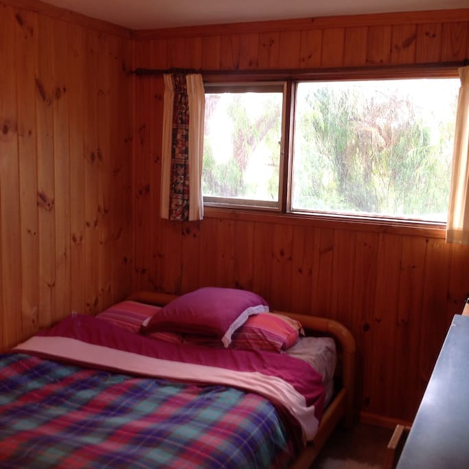 Cabin queen-sized bed and window looking north west to the bay