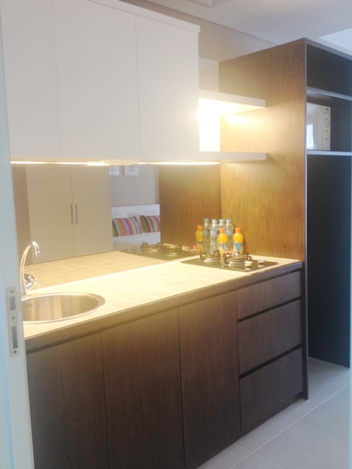 Kitchen area with 2 burner gas top complete with microwave and medium size refrigerator