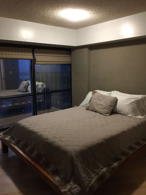 Beautiful Queen bed with luxurious linens and night view of city