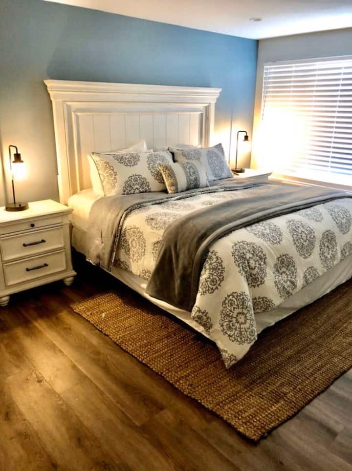 חדר שינה ראשי בקומה הראשונה עם מיטת קינג וחדר אמבטיה גדול צמוד.