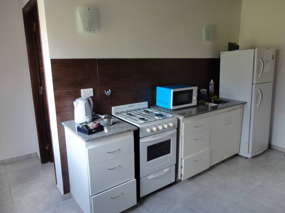 Cocina con vajilla completa. Heladera con freezer, microondas, pava eléctrica.