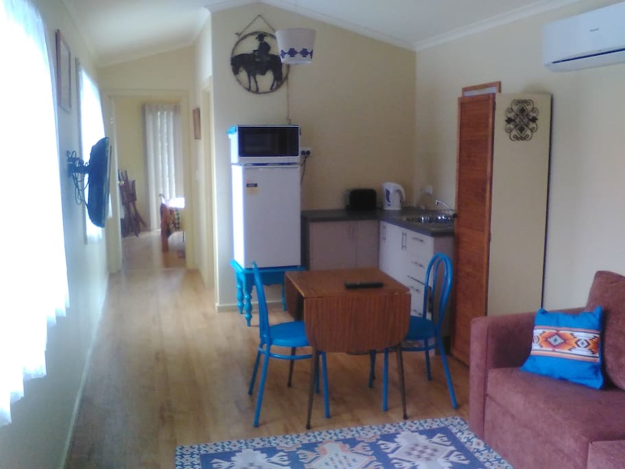 Kitchen with fridge, microwave, toaster, electric jug, sink, crockery and cutlery.