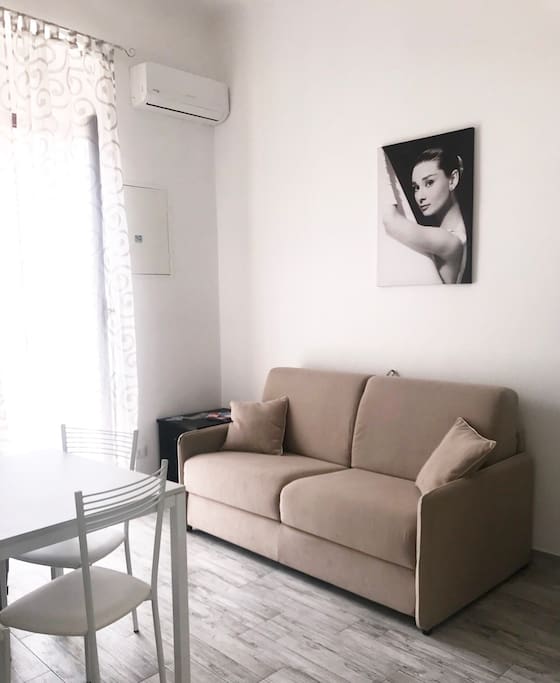 Una parte della zona giorno con comodo divano-letto + aria condizionata e accesso al balcone