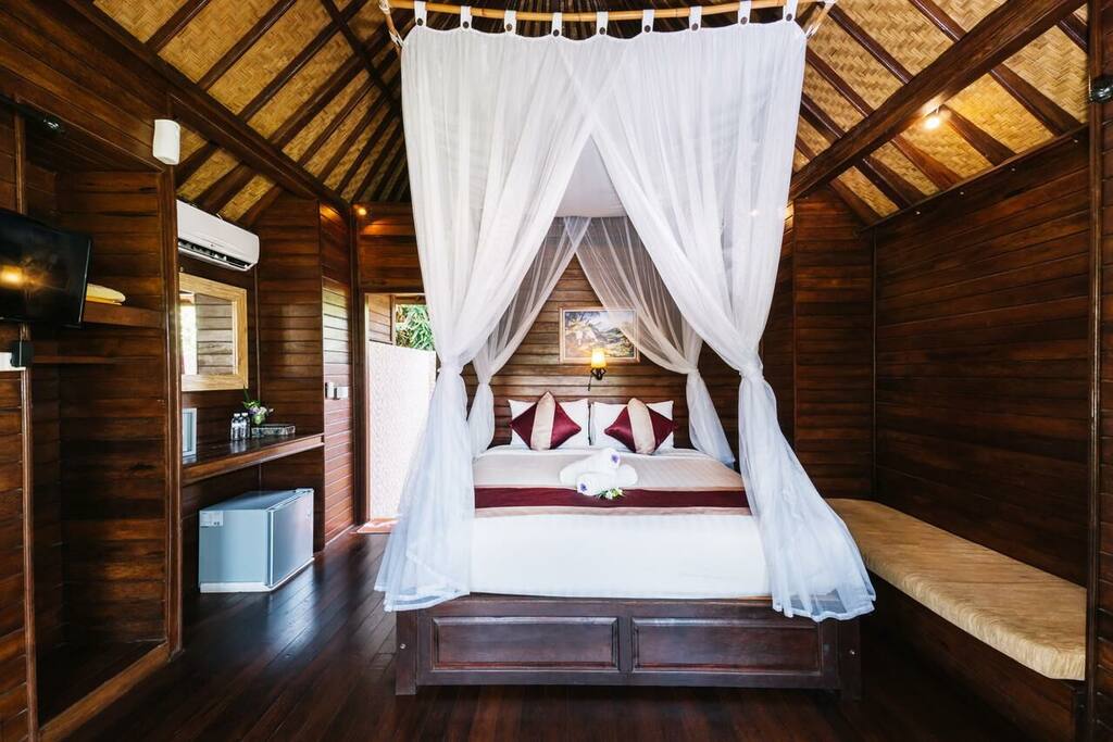 Wooden room with comfy bed, aircon, mirror, mini refrigerator, tv ,cupboard , sofa and open air bathroom