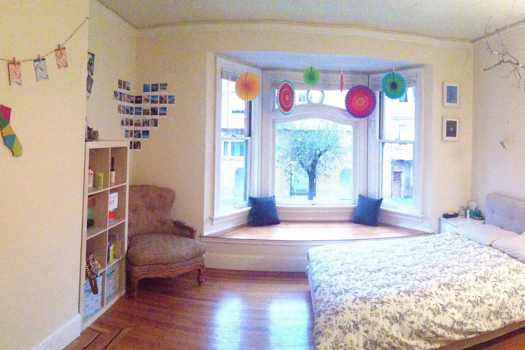A panoramic view of the bedroom. A decorative tree branch hangs above the bed.
